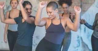 Three female ballerinas perform a synchronized dance on stage in dramatic lighting.